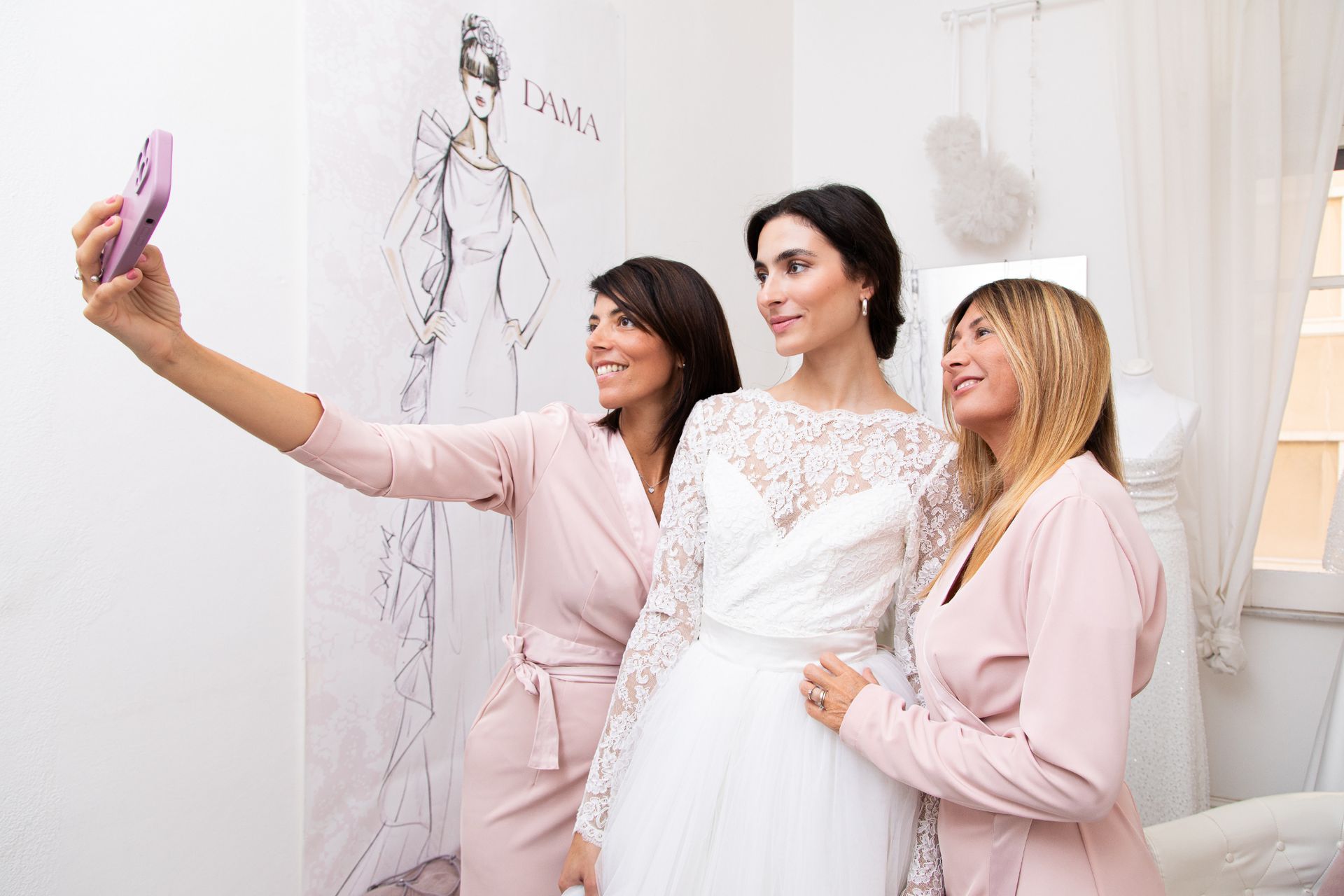Una donna in abito da sposa si scatta un selfie con altre due donne.