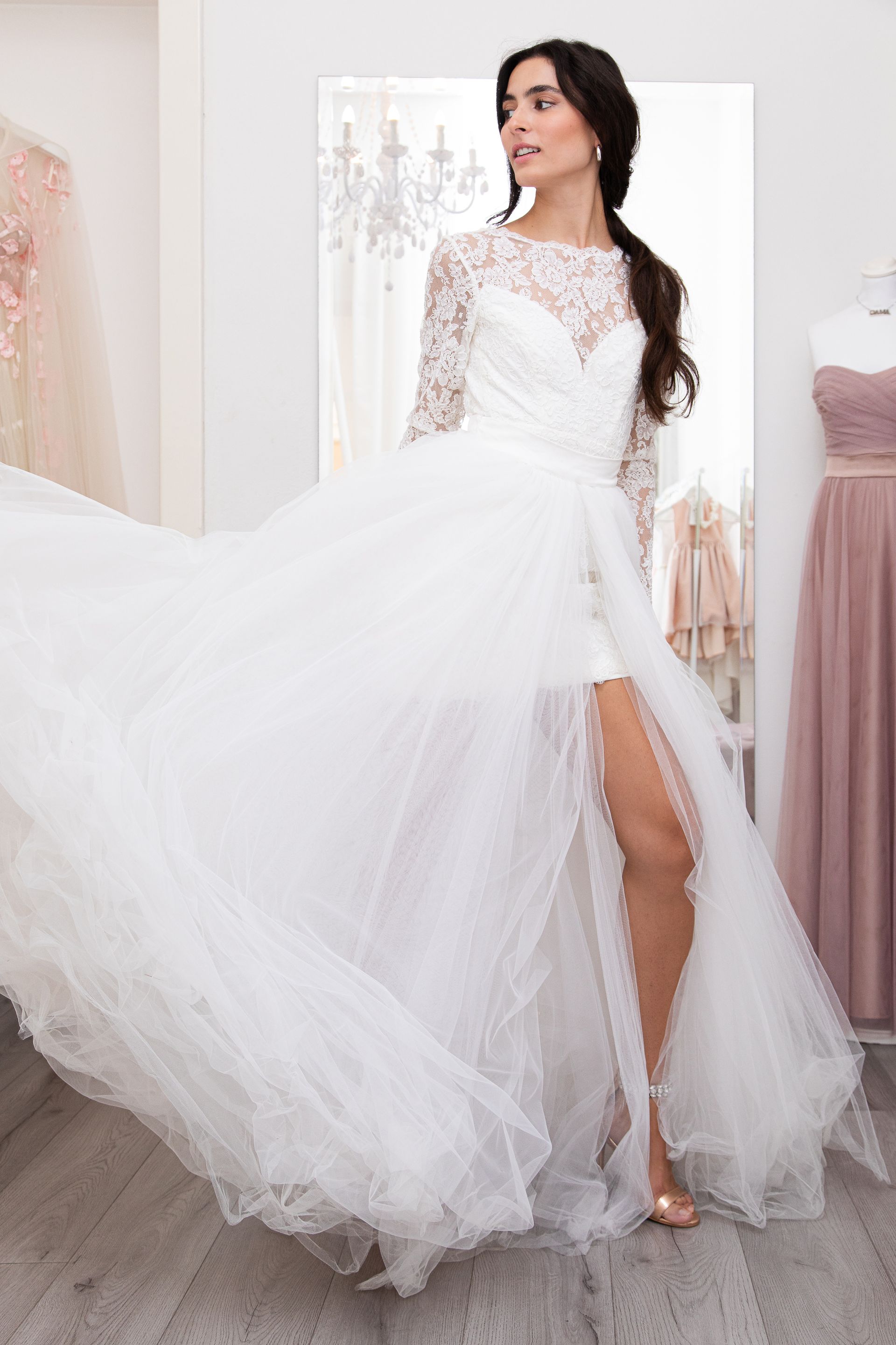 Una donna in abito da sposa bianco è in piedi davanti a uno specchio.