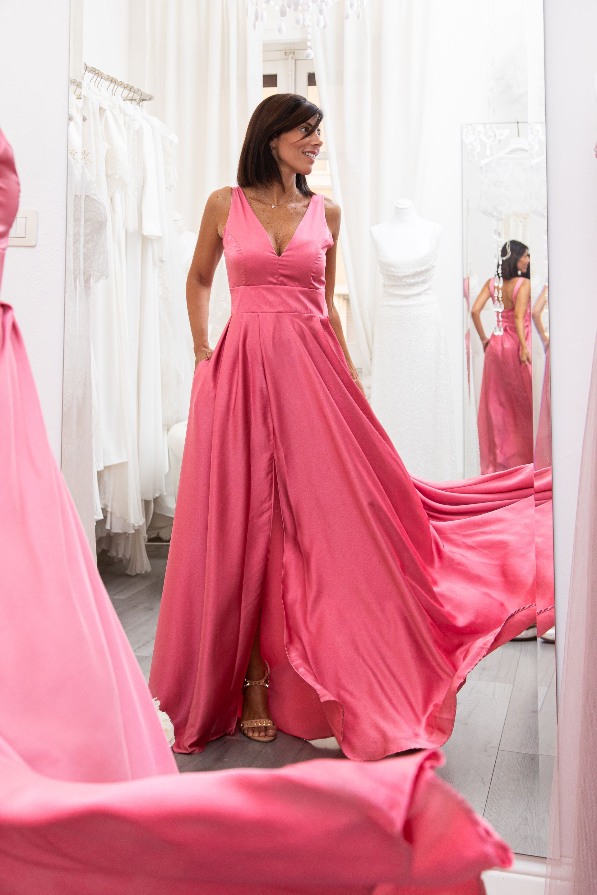 Una donna sta provando un vestito rosa davanti a uno specchio.