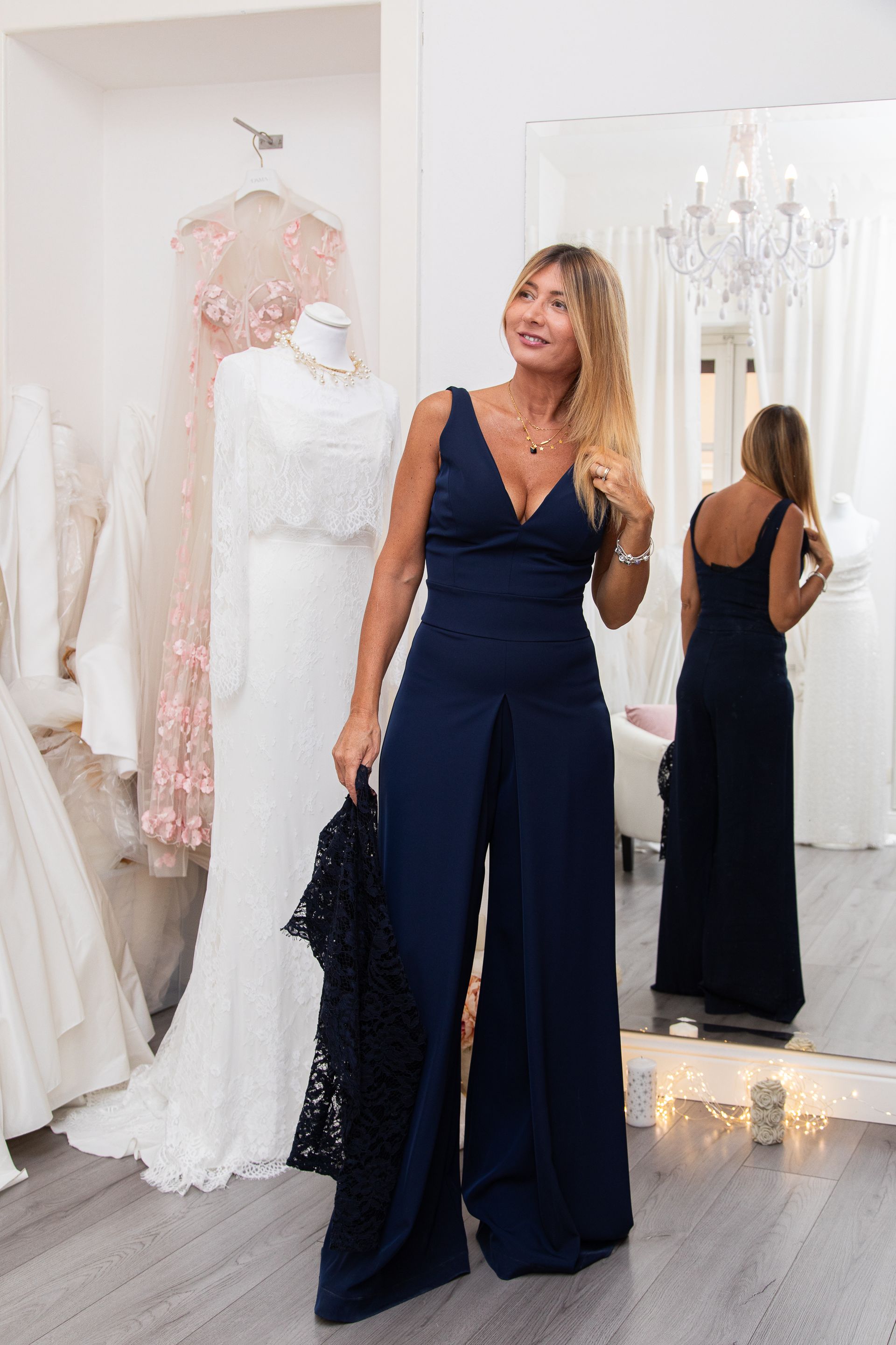 Una donna è in piedi davanti allo specchio e indossa una tuta blu.