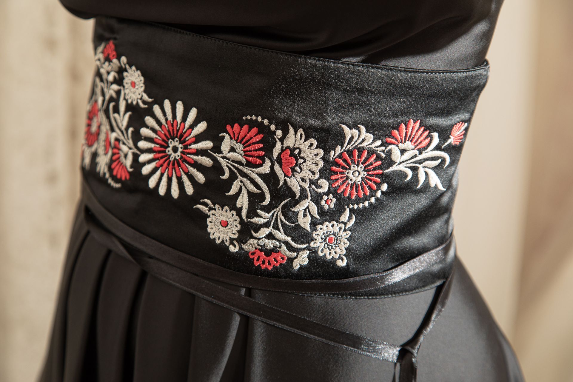 Un primo piano di un vestito nero con fiori ricamati sopra