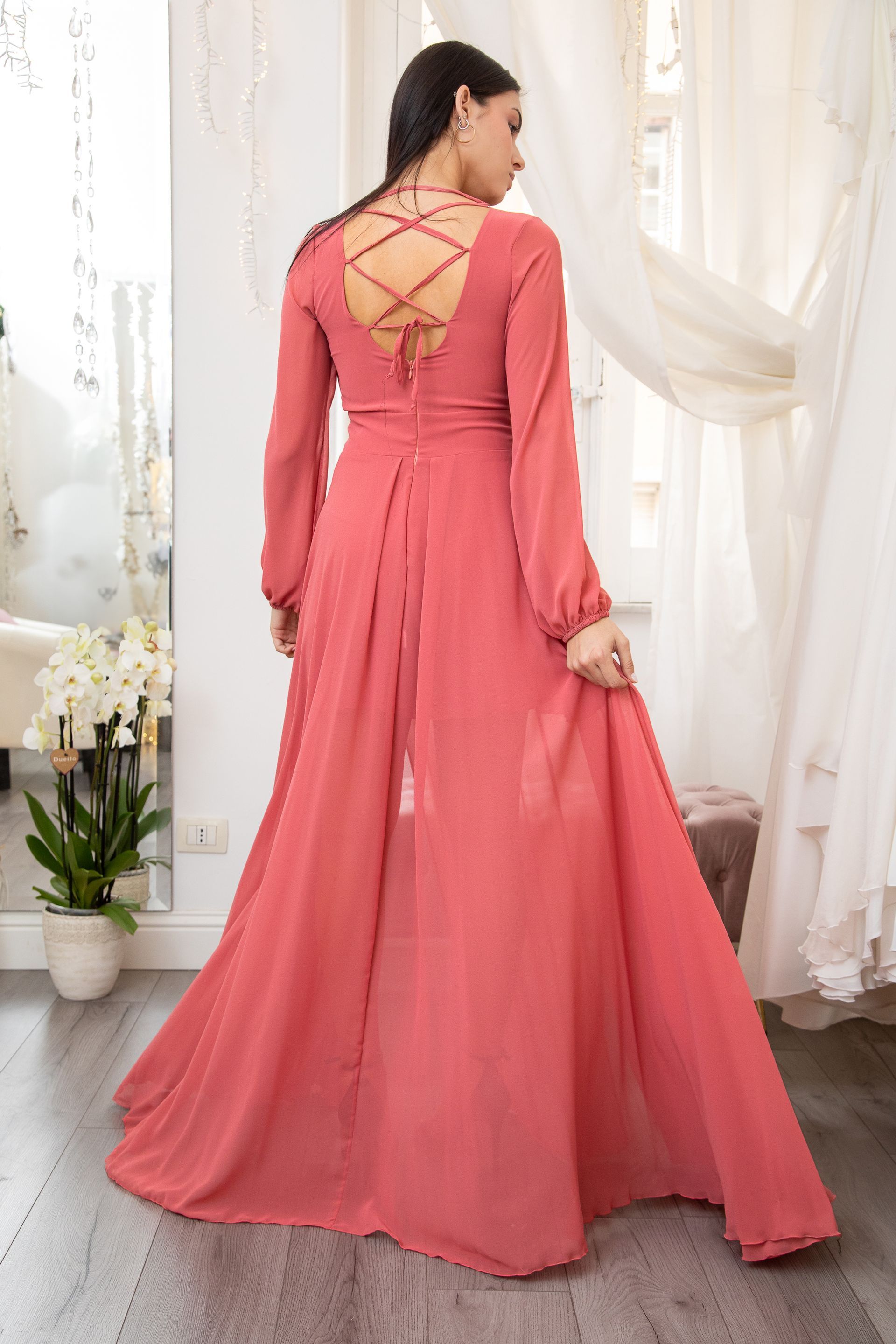 Una donna indossa un lungo abito rosa in un negozio di abiti da sposa.