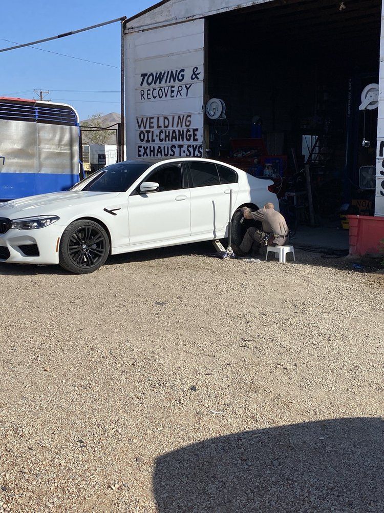 White BMW being worked on in front of a garage with 