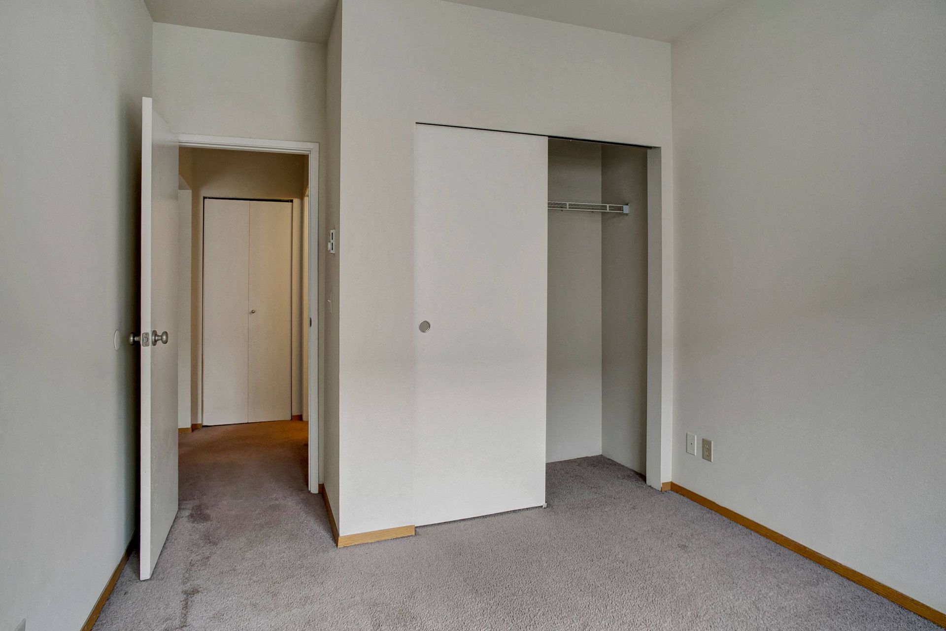 An empty bedroom with a closet and a door.