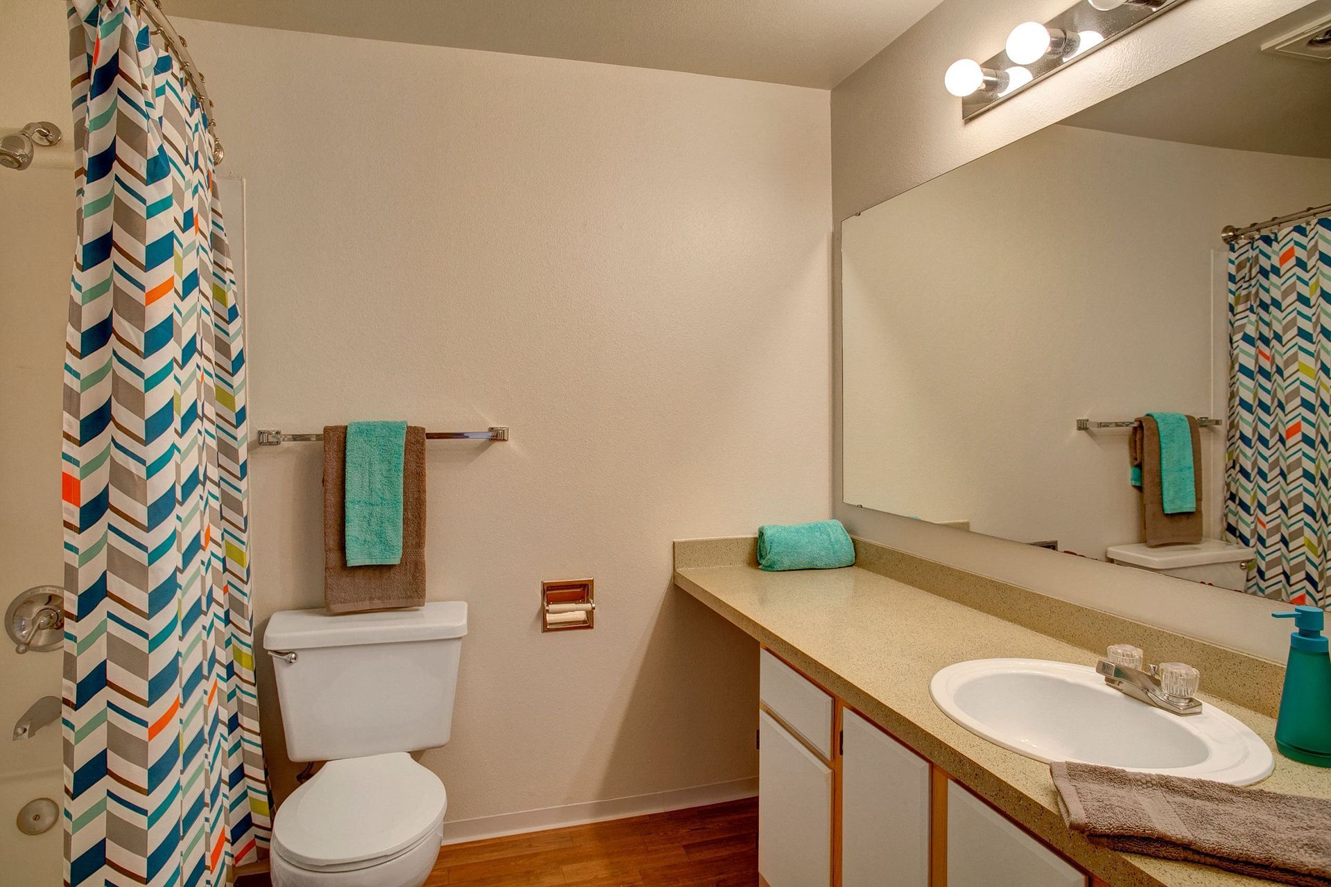 A bathroom with a toilet, sink, and mirror.
