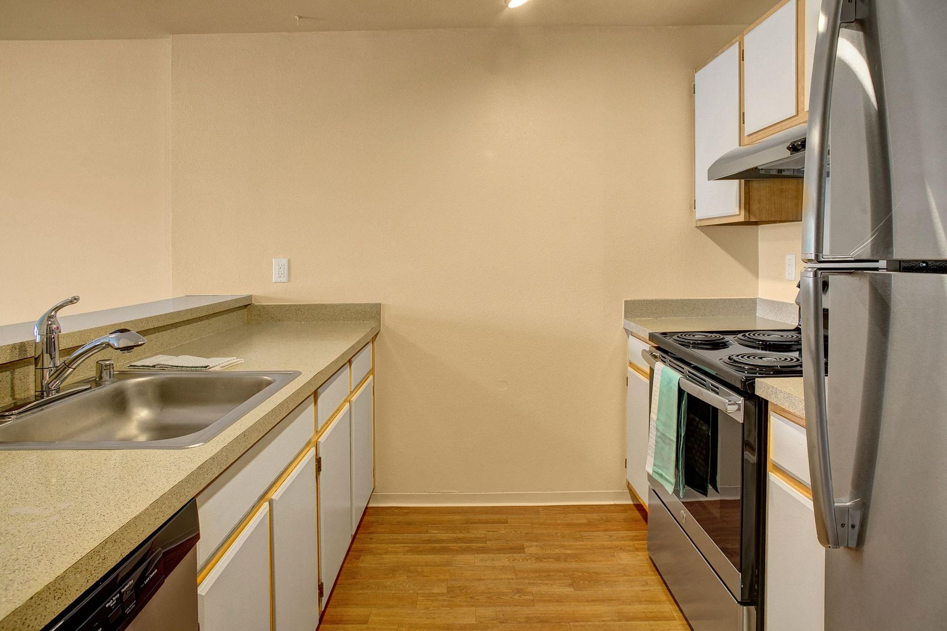 A kitchen with a sink, stove, refrigerator, and dishwasher.