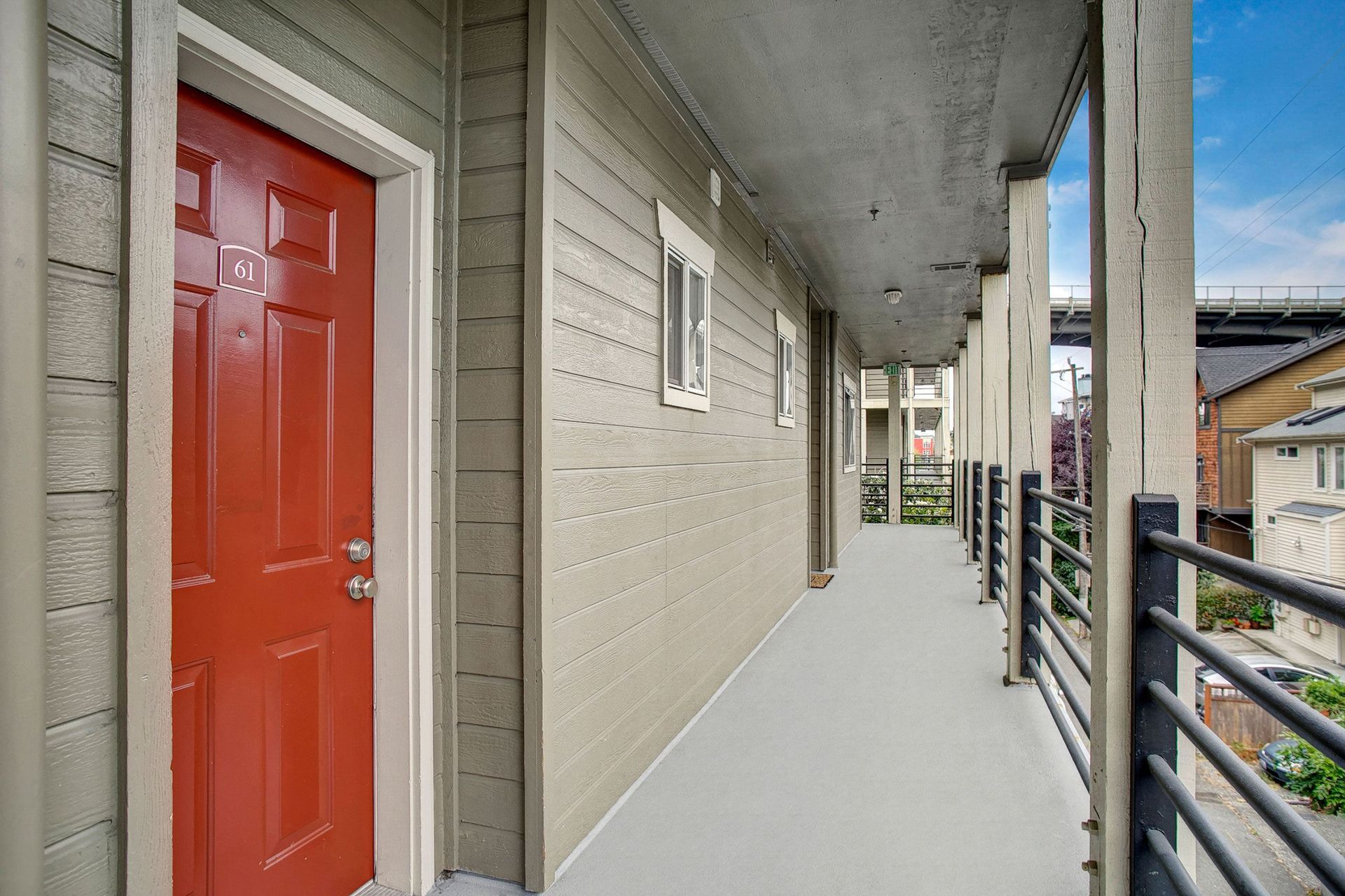 A red door is on the side of a building next to a balcony.