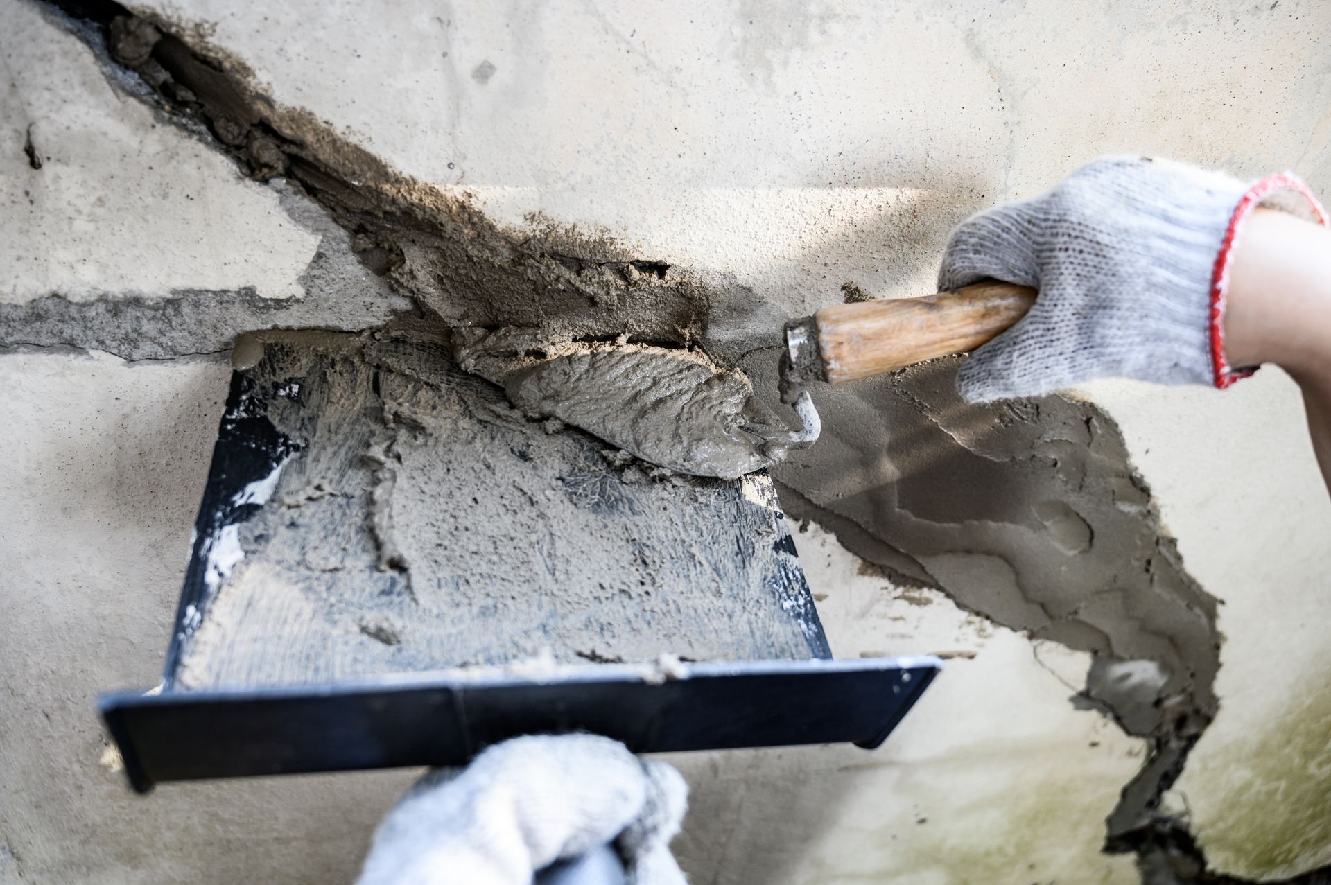 A handyman wearing protective gear is repairing a section of damaged concrete.