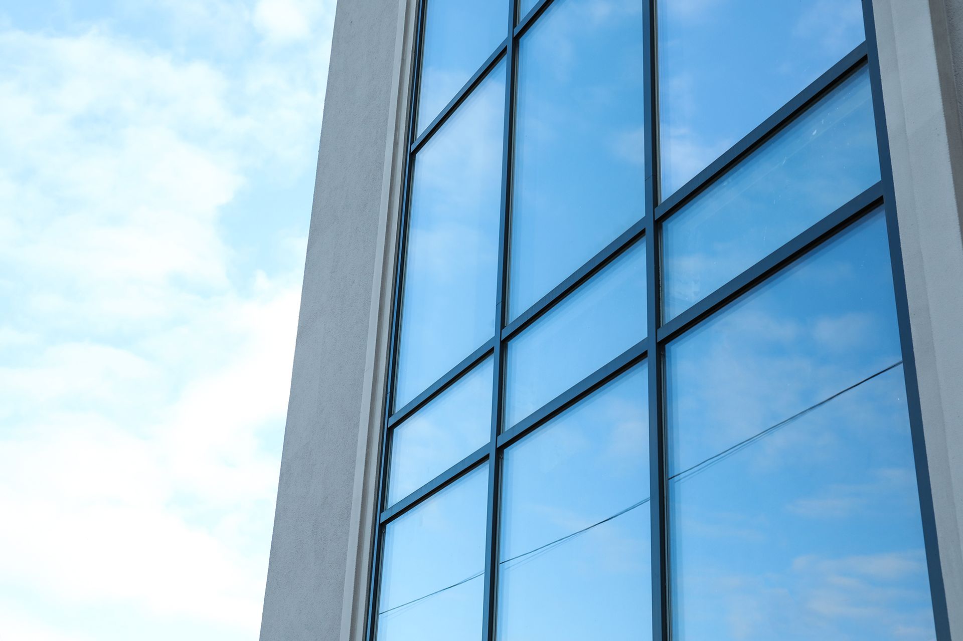 Blue sky reflected in the windows of a modern white building.