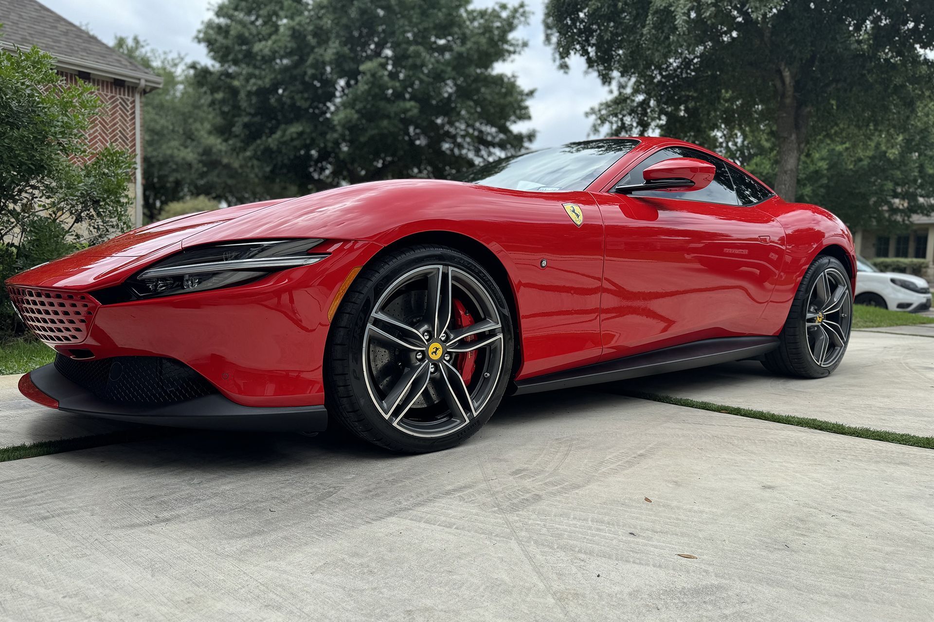 A red ferrari is parked in a driveway in front of a house.