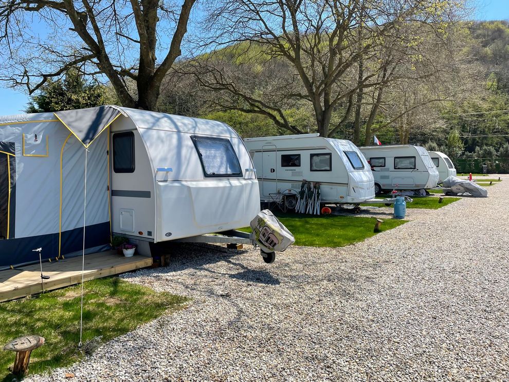 a row of caravans parked next to each other in a gravel area .