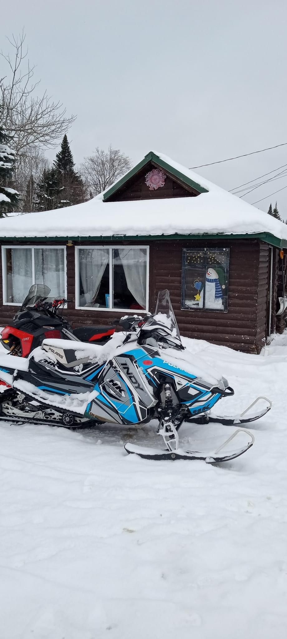 a snowmobile is parked in front of a snow covered house .