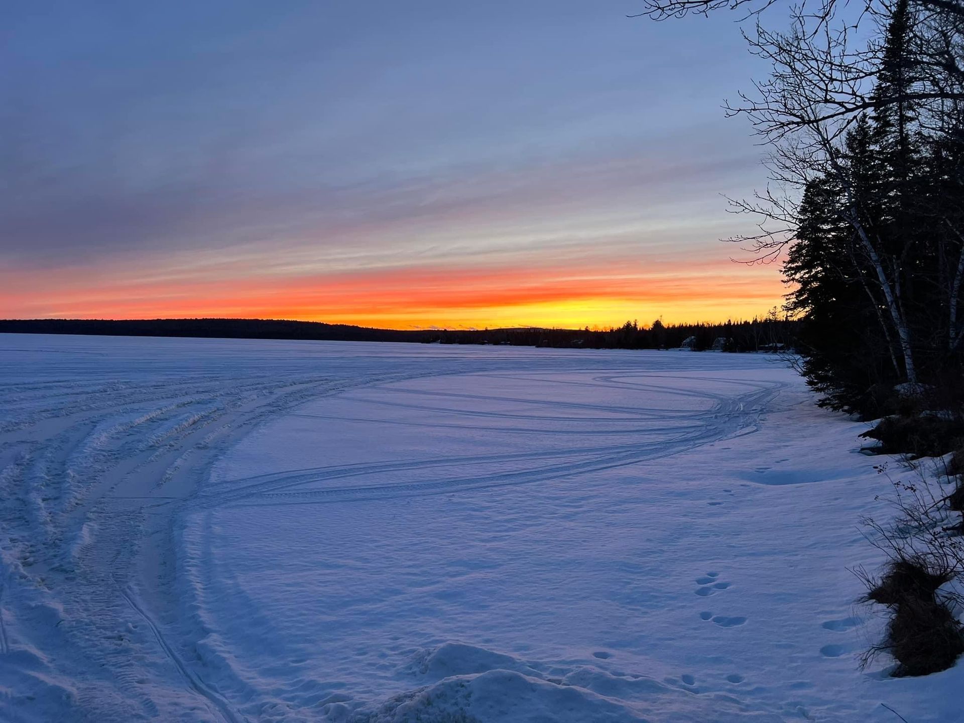 a snowy field with a sunset in the background