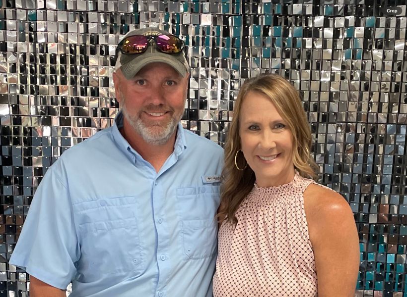 A man and a woman are posing for a picture in front of a wall.