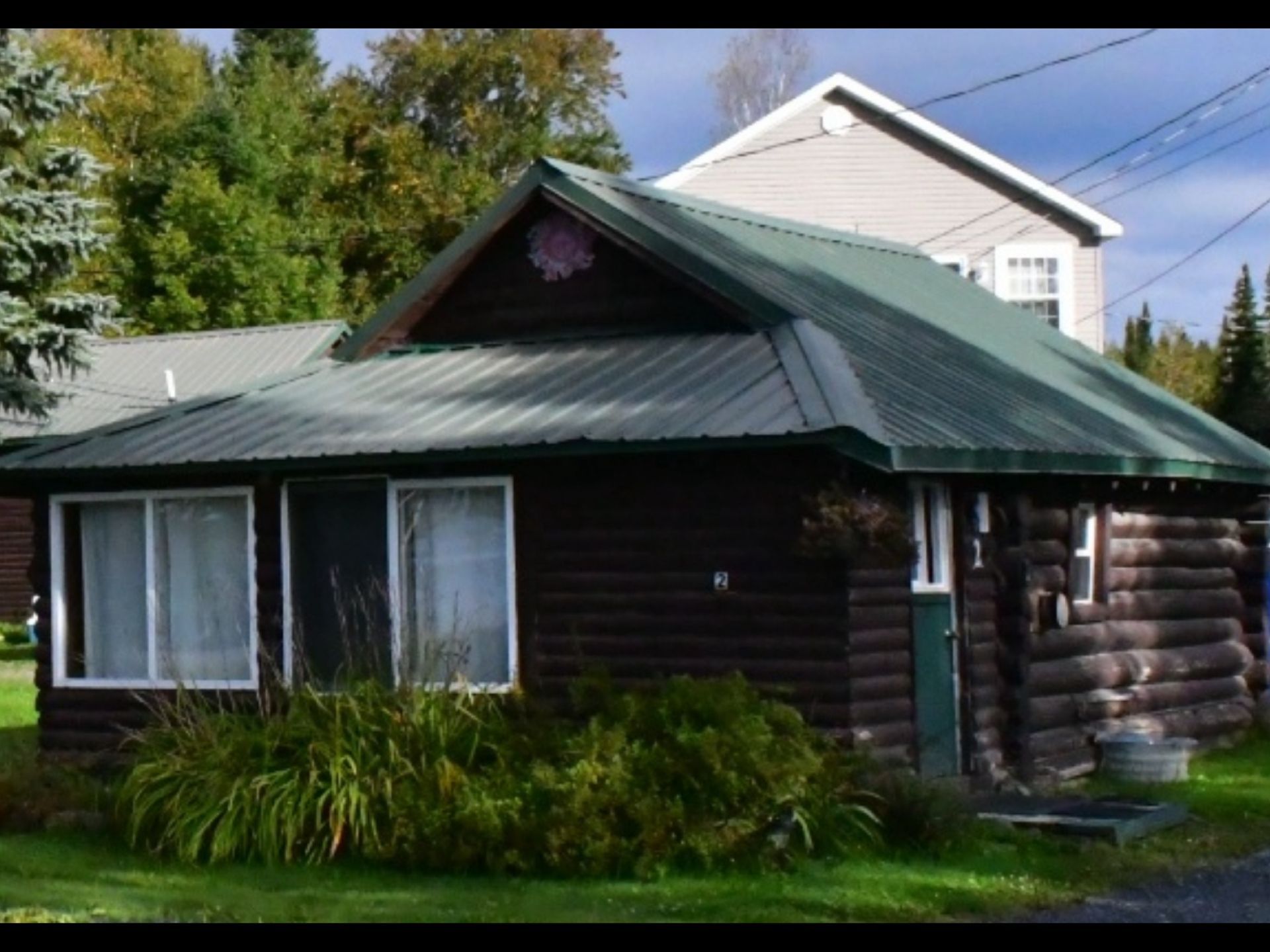 a small log cabin with a green roof and a picnic table in front of it .