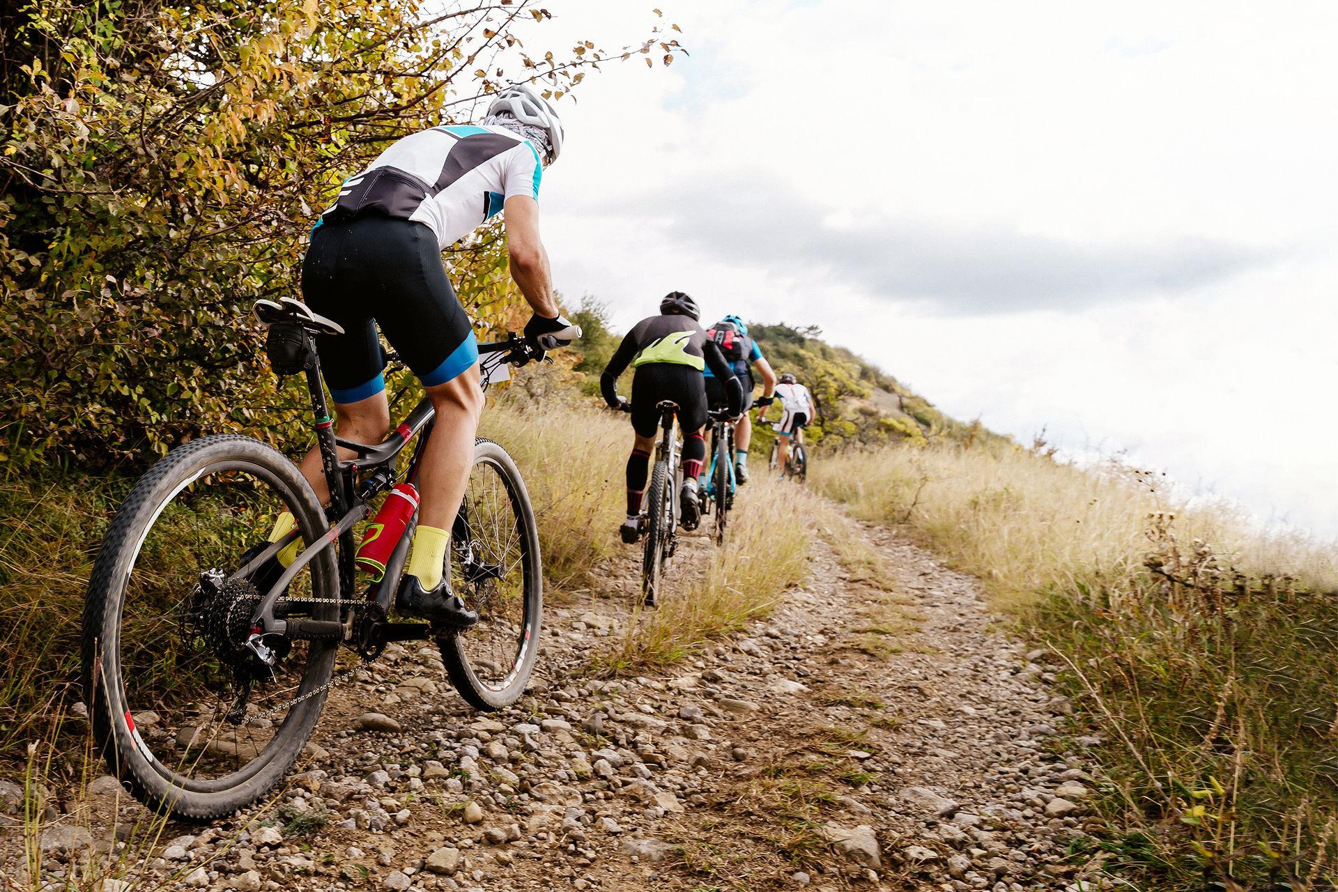 a group of people are riding bicycles down a dirt road .