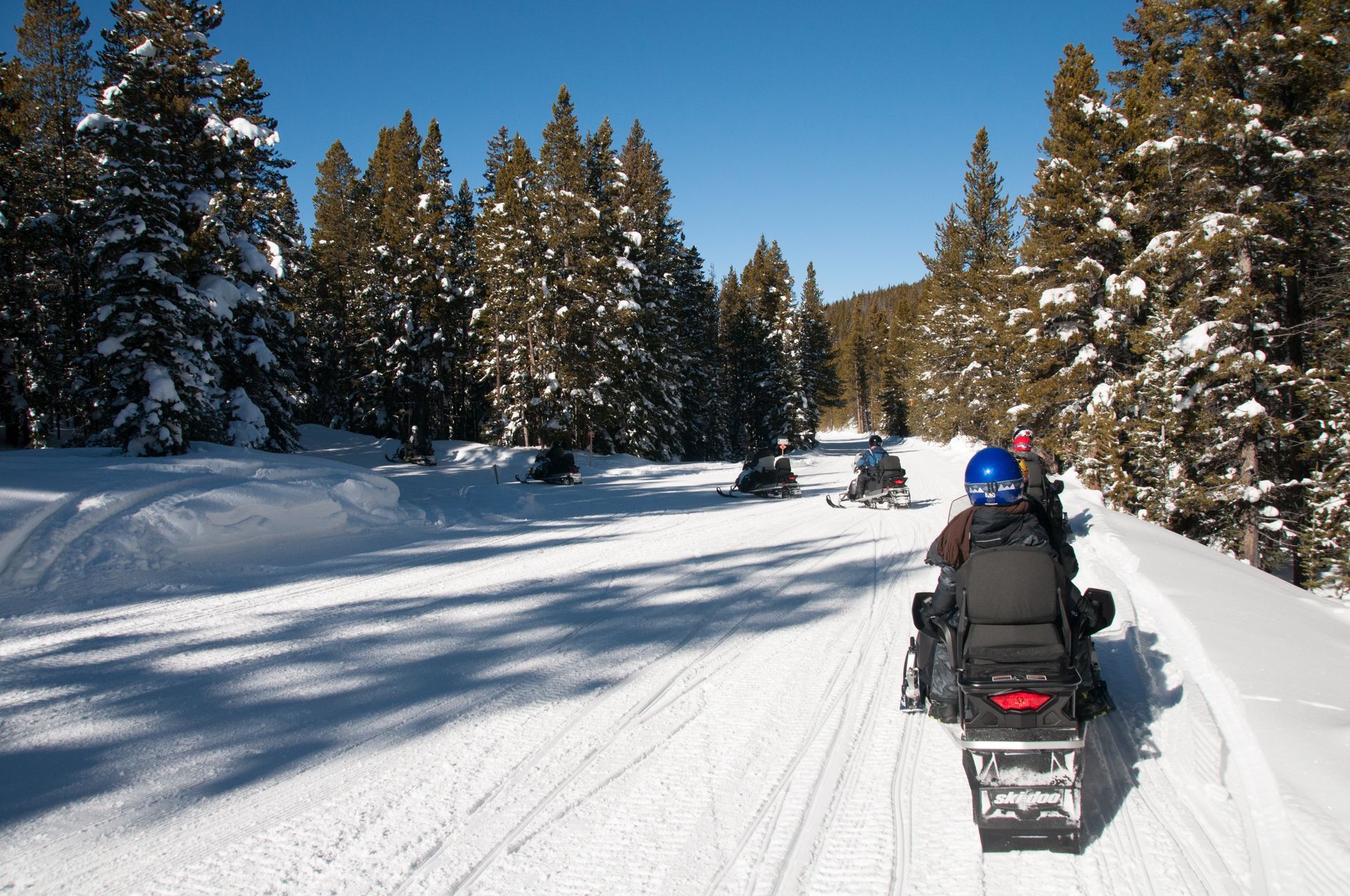 a group of people are riding snowmobiles down a snowy road