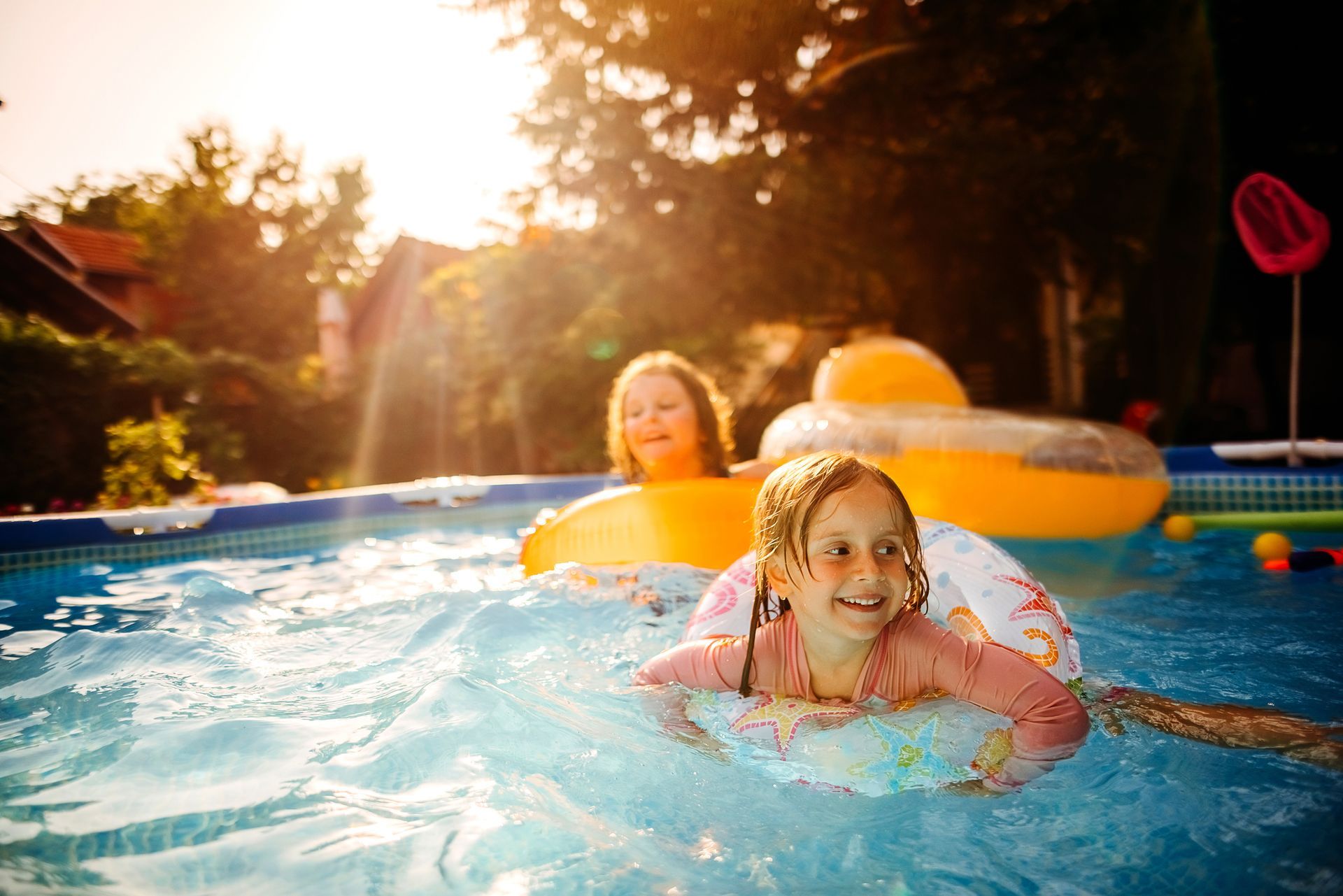 Children playing in a pool with inner tubes on a sunny day.