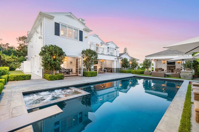 White house with pool and patio at dusk.
