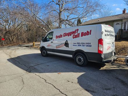 A white van is parked on the side of the road in front of a house.