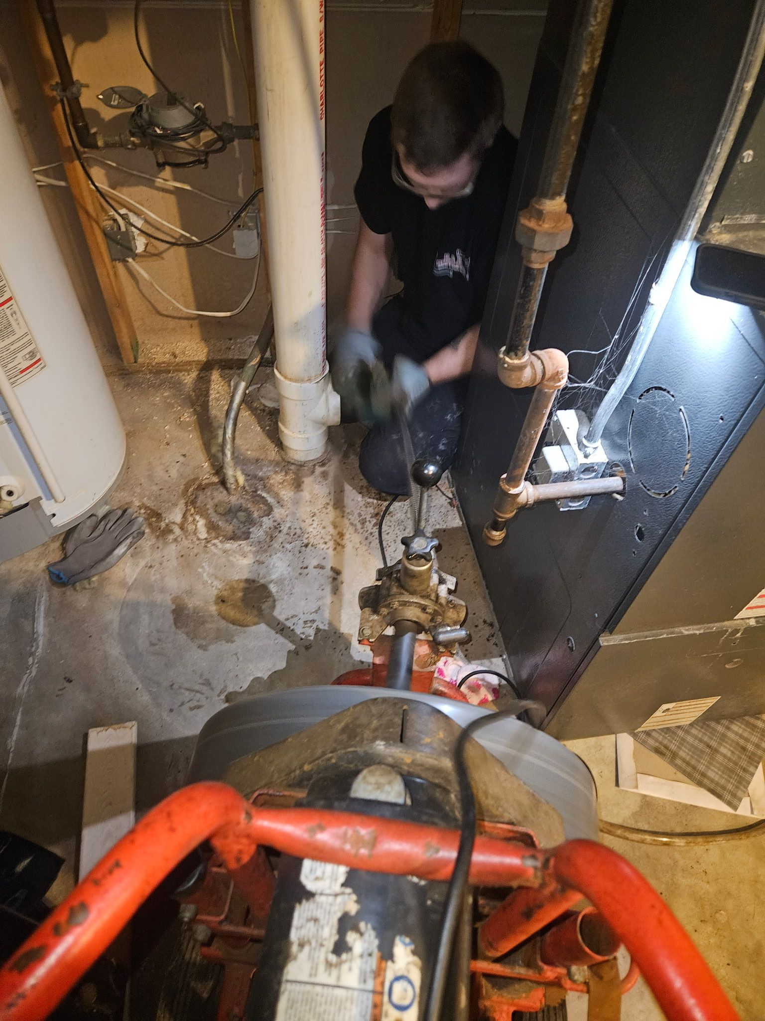 A man is working on a pipe in a basement.