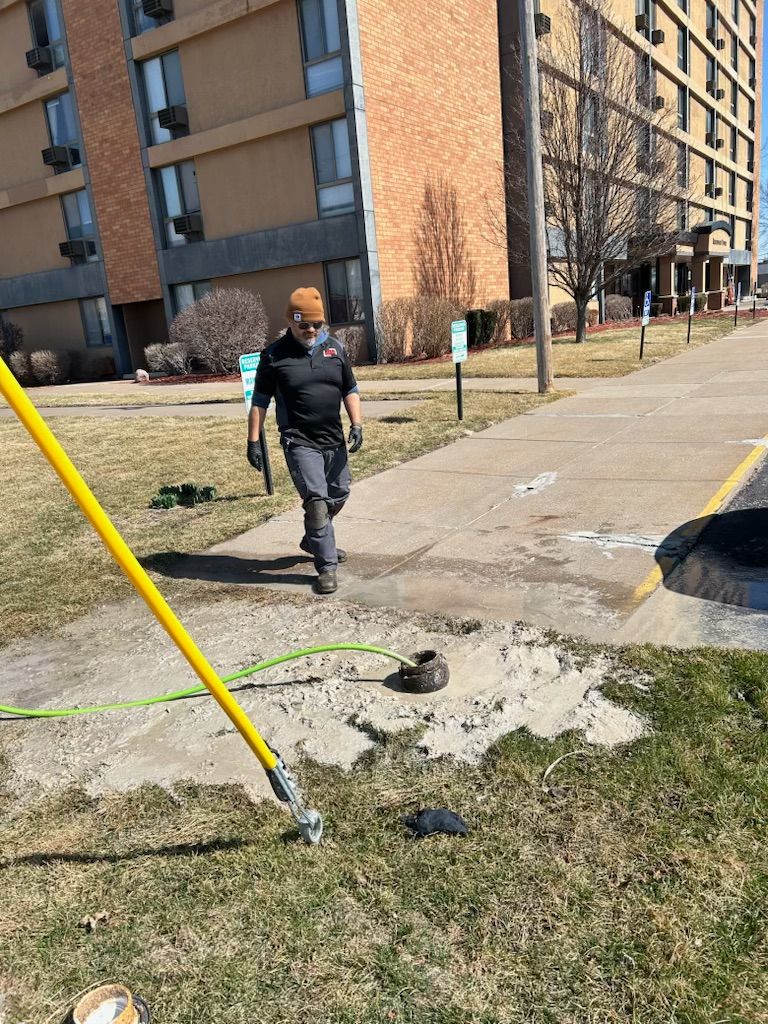 A man is walking down a sidewalk next to a yellow pole.