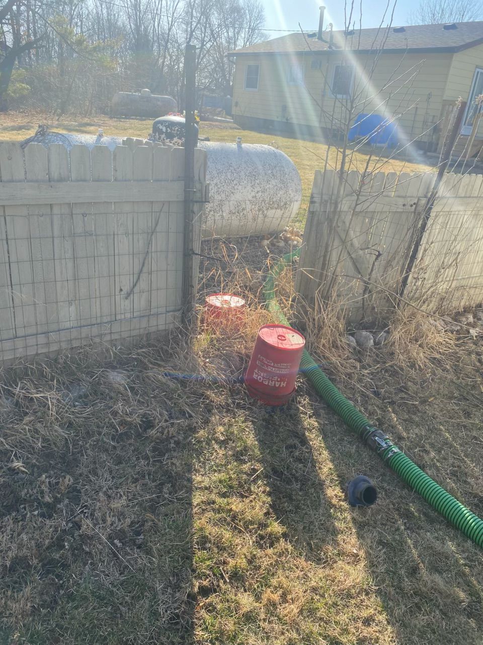 A hose is sitting in the grass next to a brick wall.