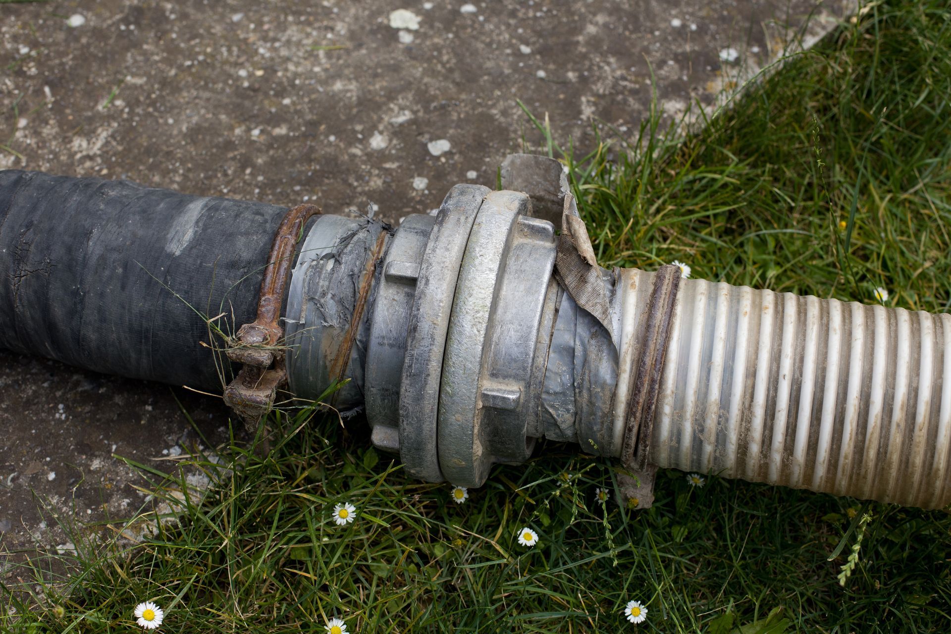 A man with a tattoo on his arm is using a vacuum cleaner to clean a toilet.