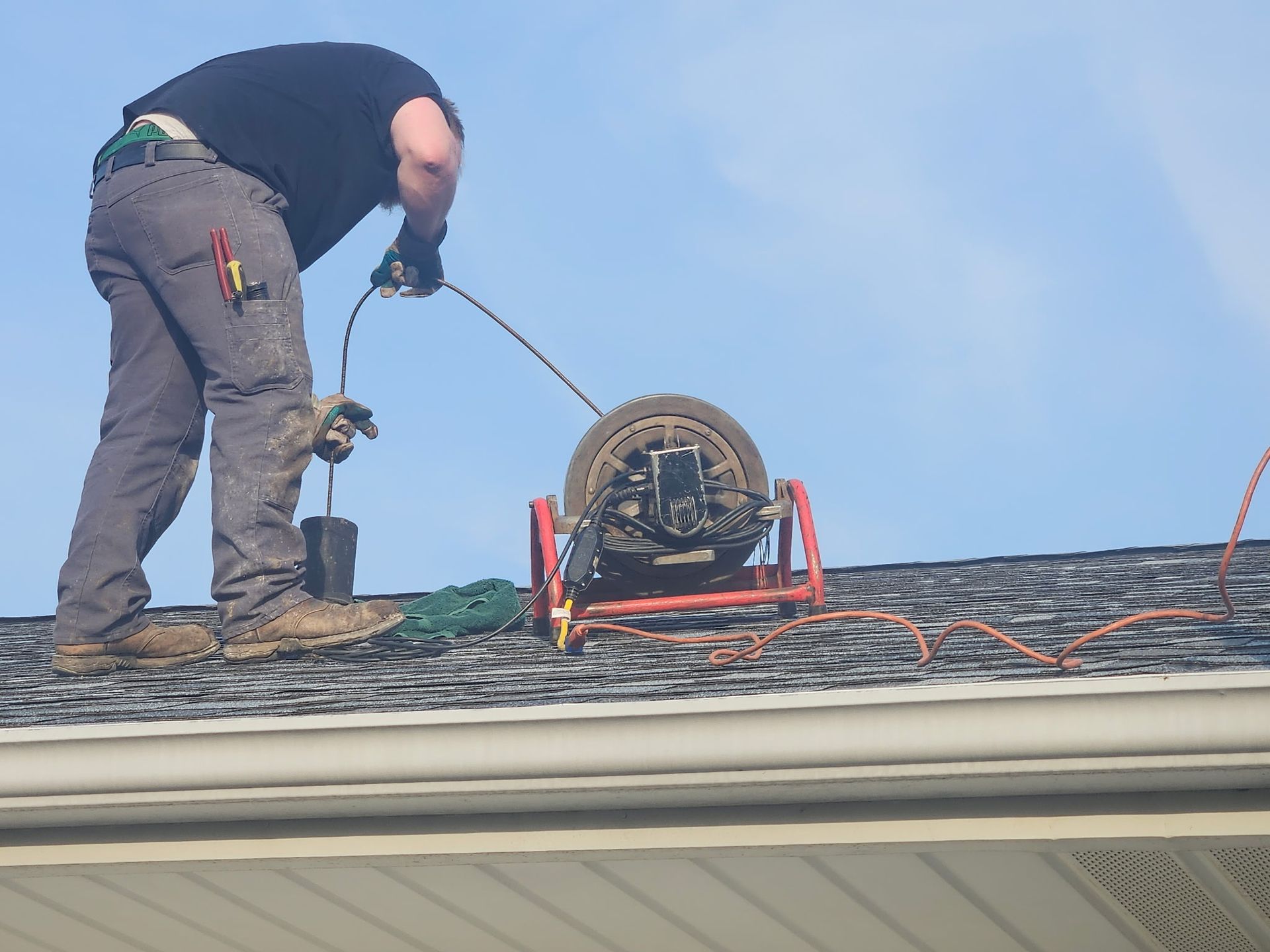 A man is standing on top of a roof with a camera attached to it.