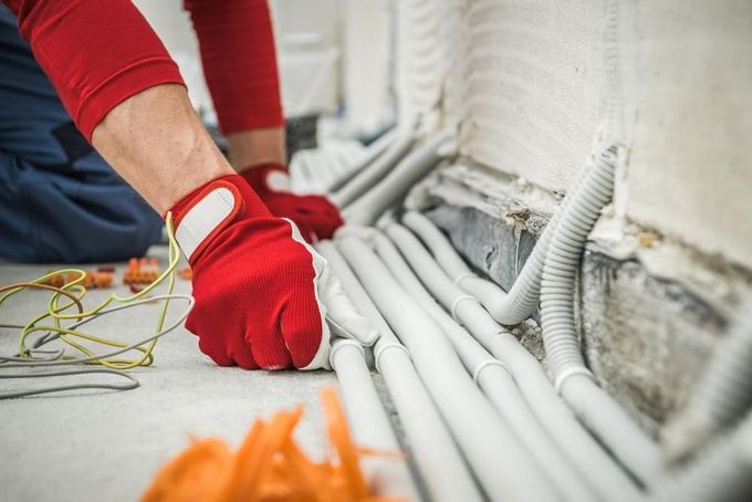 A Man is Kneeling on the Floor Working on Electrical Wires — Young Building In Pampoolah, NSW