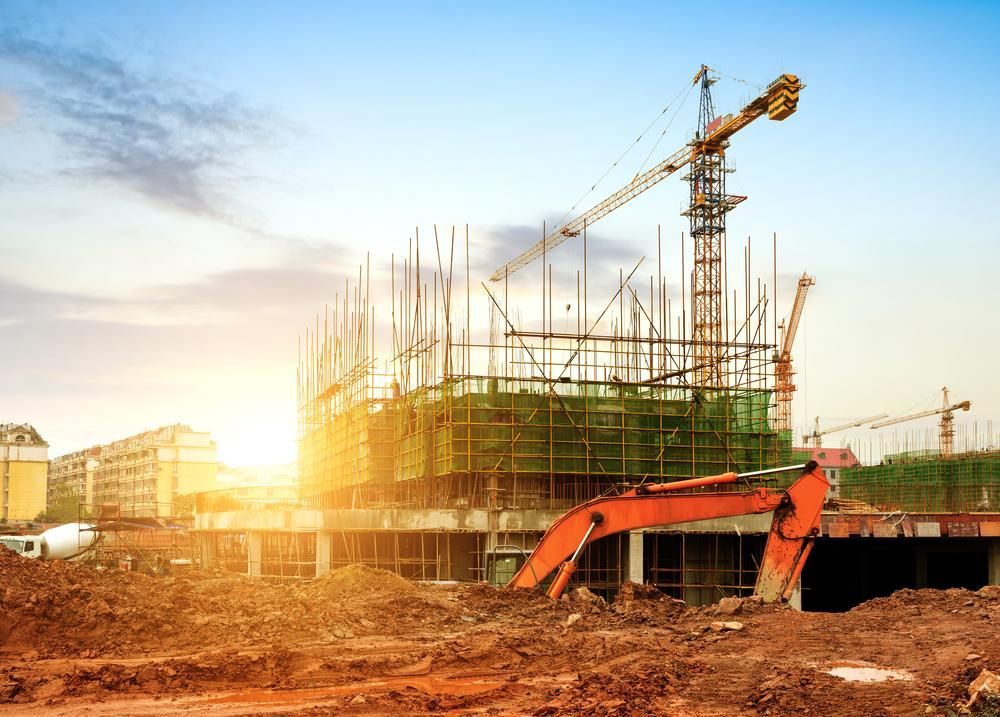 A Construction Site With a Crane and an Excavator in the Foreground — Young Building In Forster, NSW