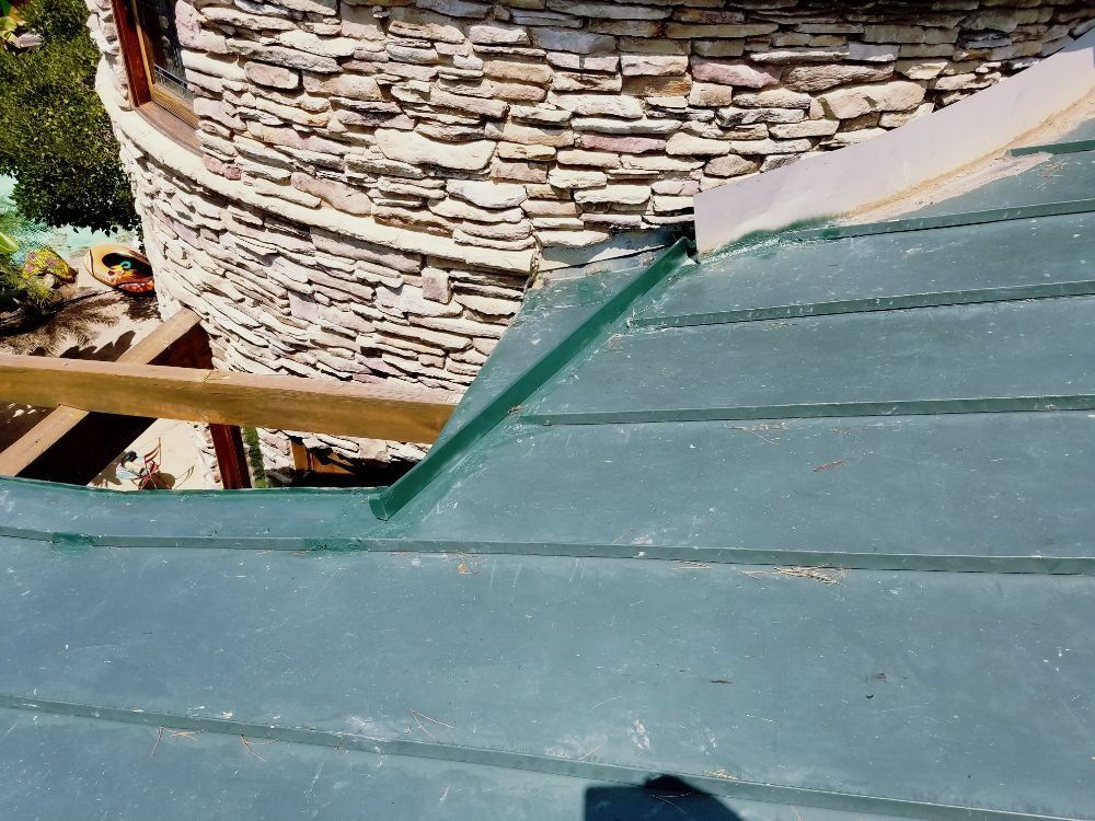 A green roof with a stone wall in the background