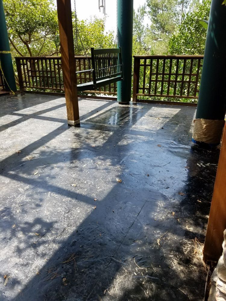 There is a porch with a swing and a fence.