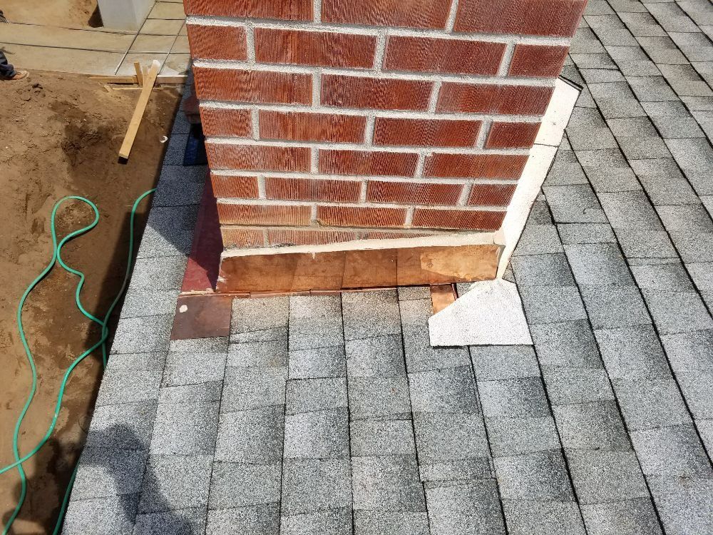 A brick chimney is sitting on top of a roof.