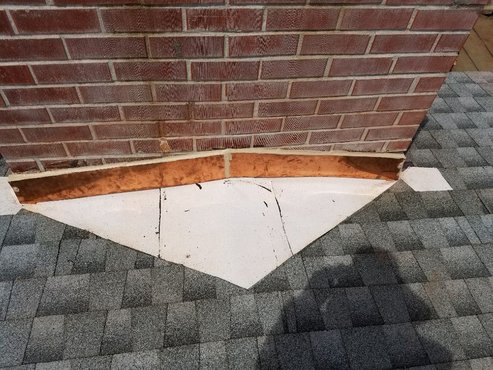 A close up of a brick wall with a roof in the background.