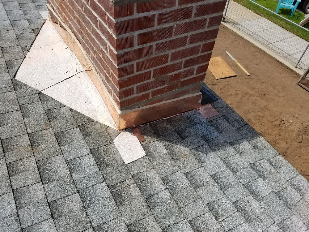 A brick chimney is sitting on top of a roof.