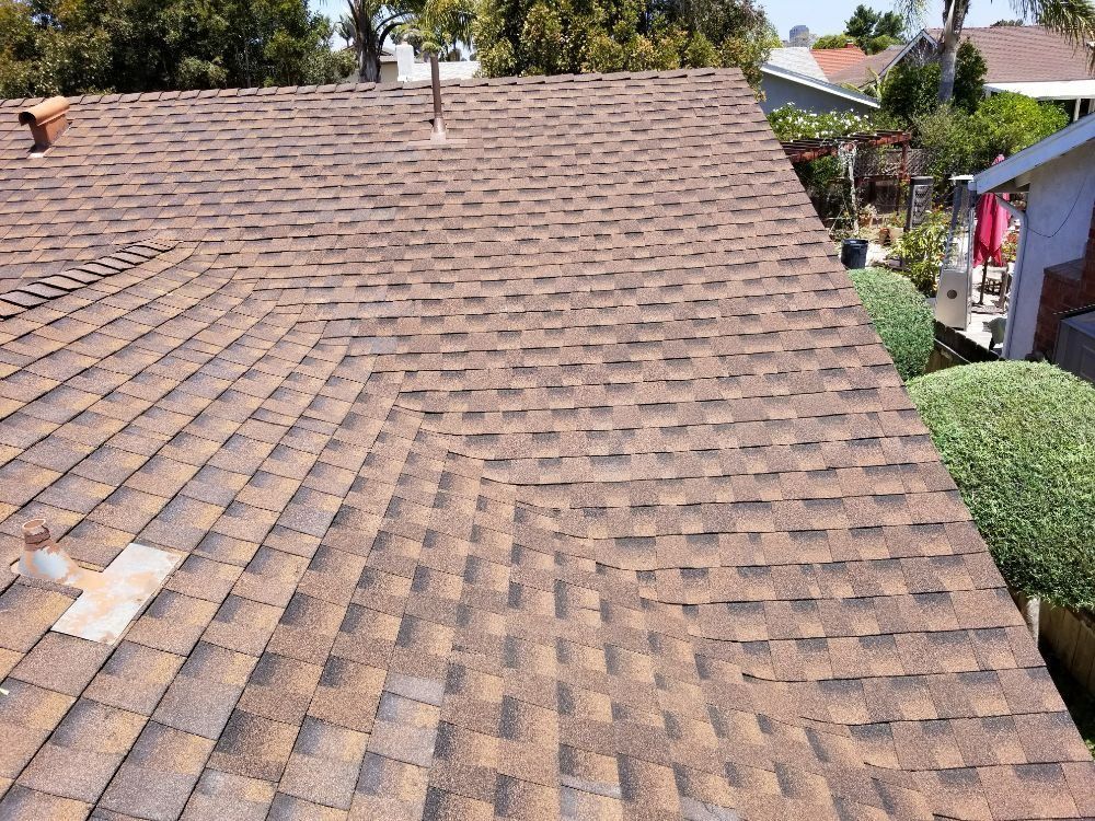 The roof of a house with a brown shingle roof.