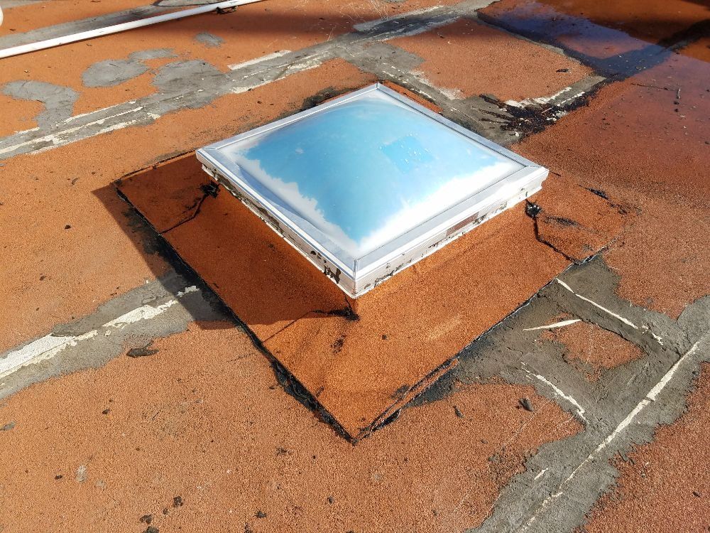 A skylight is sitting on top of a brick roof.