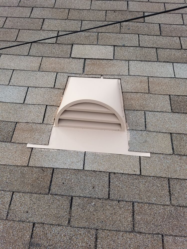 A white vent is sitting on top of a brick roof.