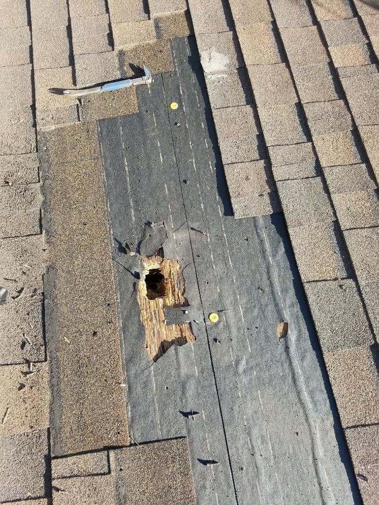 A roof with a hole in it and a hammer on top of it.