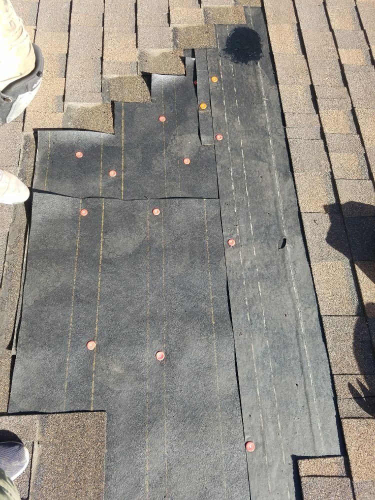 A person is standing on a roof with a lot of shingles on it.