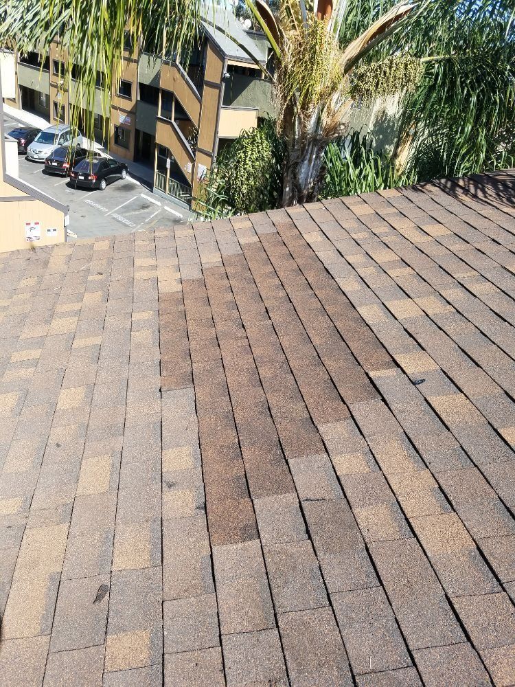 A roof with a lot of shingles on it and a parking lot in the background.