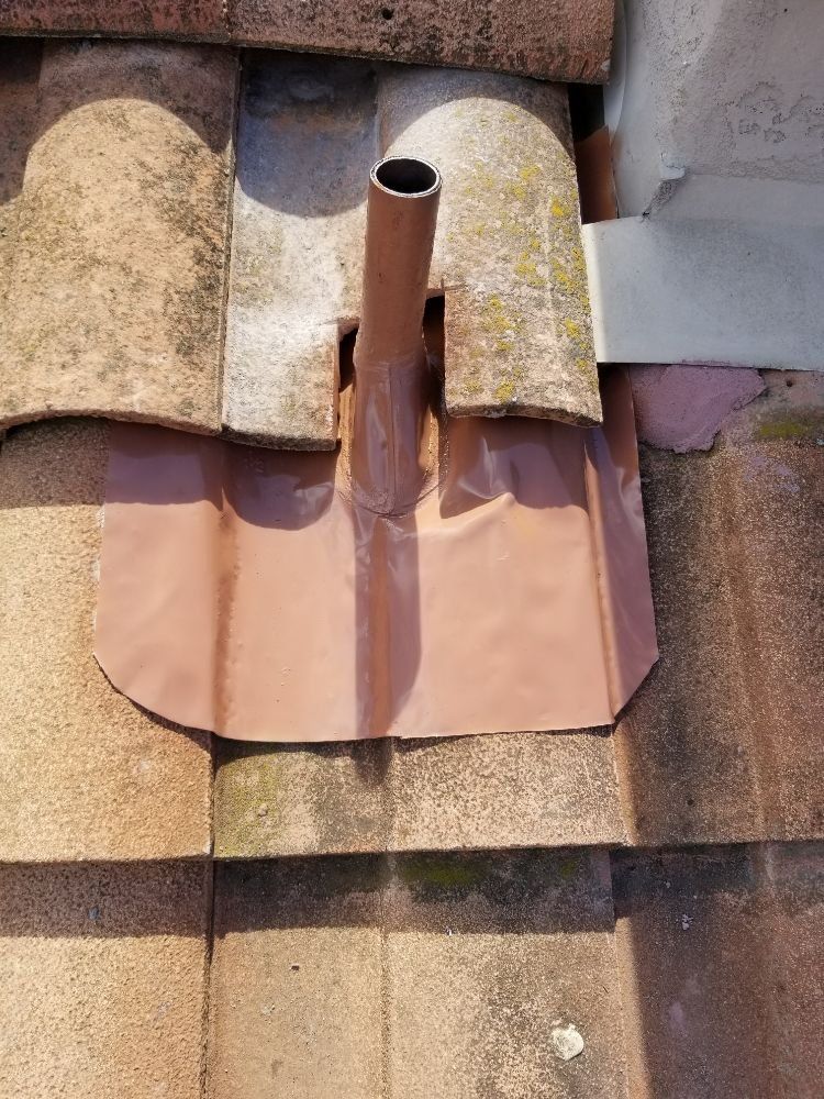 A pipe is sitting on top of a tiled roof.