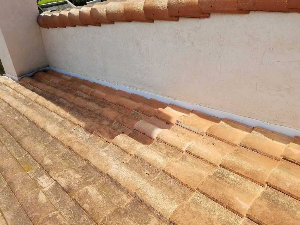 A close up of a tiled roof next to a wall.