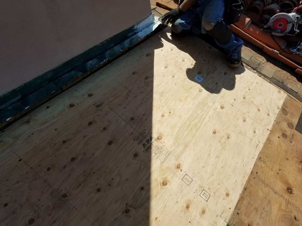 A person is kneeling on a piece of plywood.