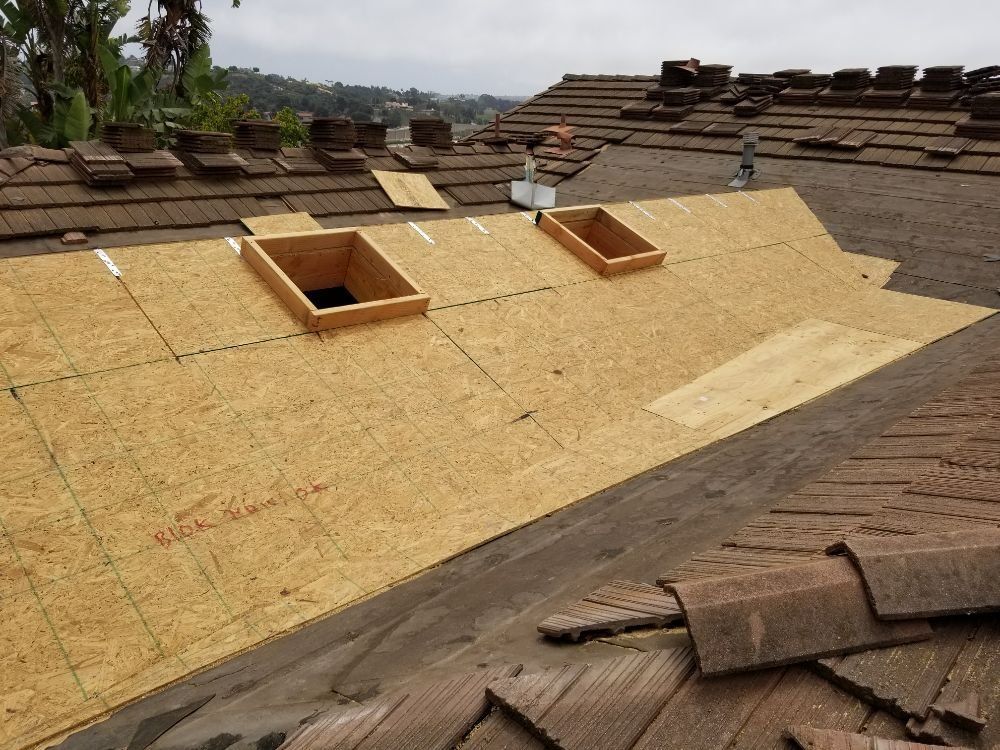 The roof of a house is being remodeled and has two skylights on it