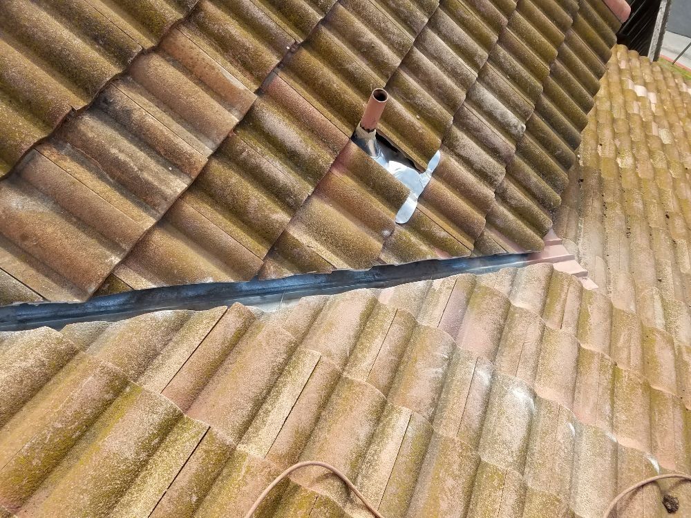 A close up of a tiled roof with a hole in it.