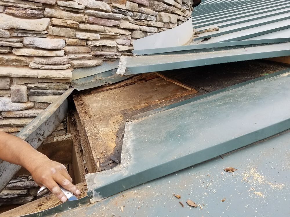 A person is working on a roof with a spatula.