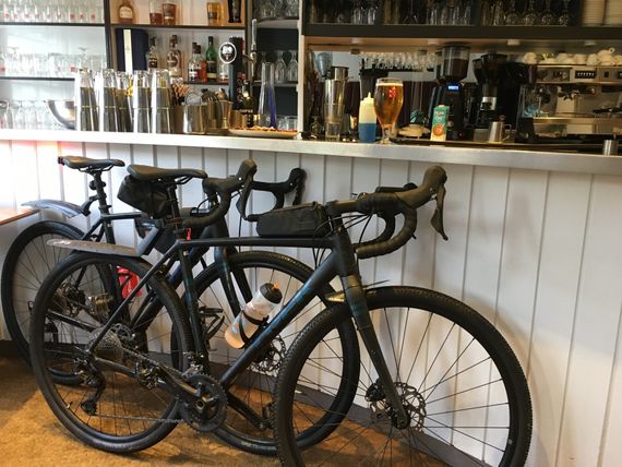 two bicycles are parked in front of a bar that has a bottle of beer on it