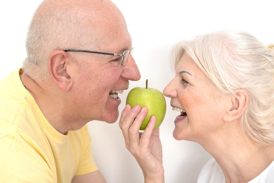 Senior Couple Eating Green Apple — Grand Rapids, MI — Dentures In a Day